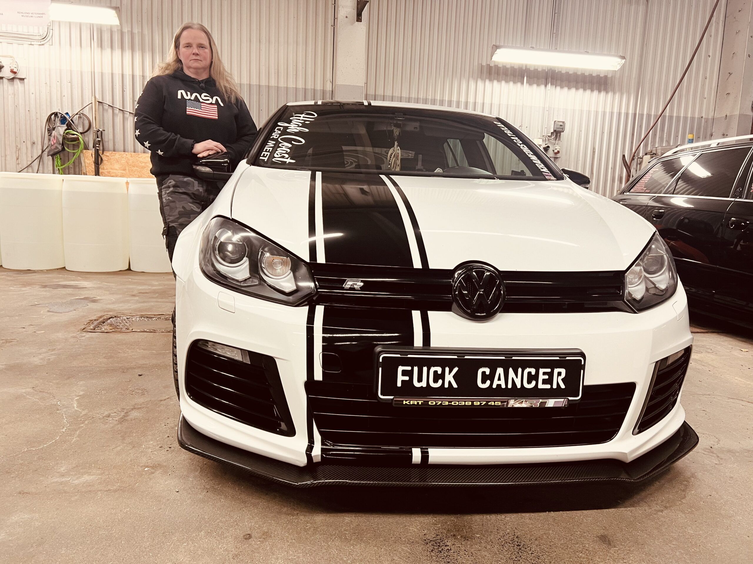 en kvinna intill en bil med nummerplåten FUCK CANCER