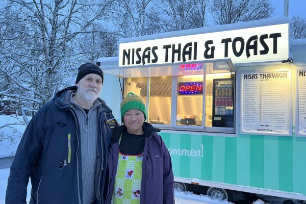 en man och en kvinna i vintermiljö framför en upplyst matvagn